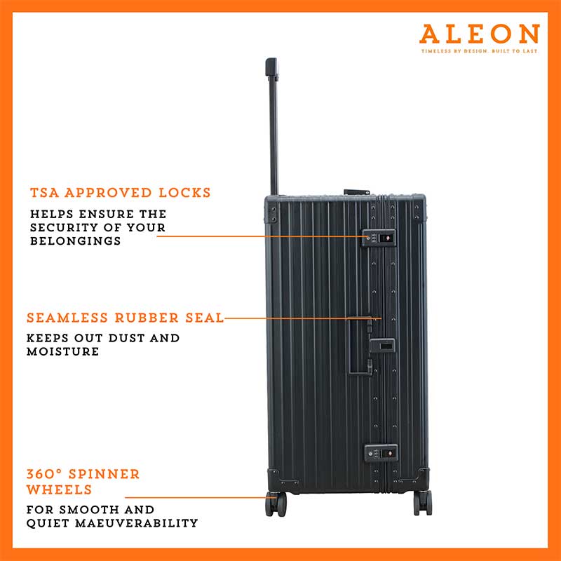 A sleek, onyx-colored aluminum trunk-style suitcase with reinforced corners and a sturdy telescoping handle. The case stands upright, showcasing its durable construction and TSA-approved combination locks.