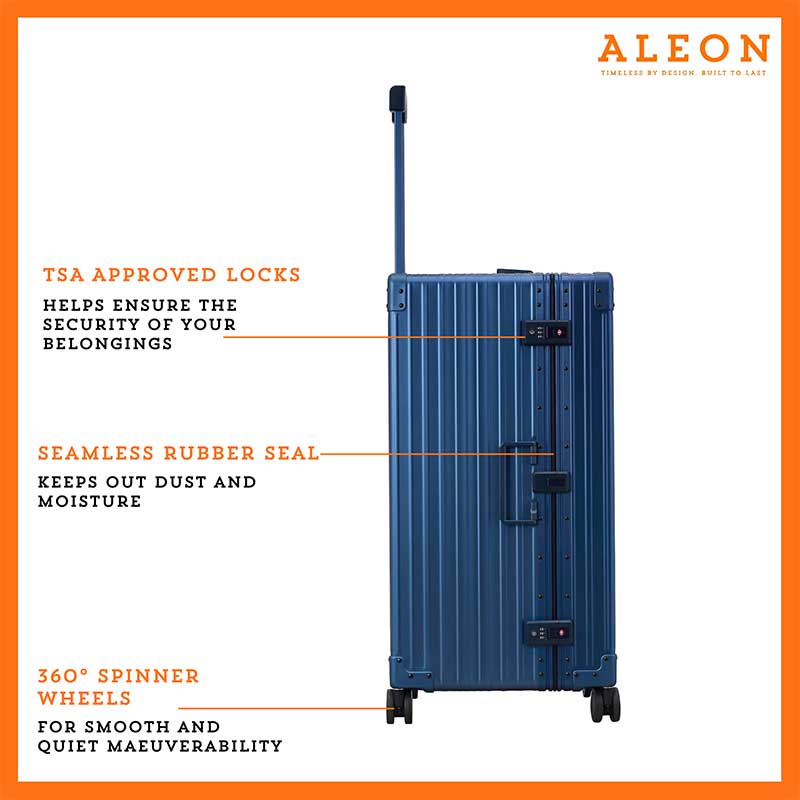 A sleek, platinum-colored aluminum trunk-style suitcase with reinforced corners and a sturdy telescoping handle. The case stands upright, showcasing its durable construction and TSA-approved combination locks