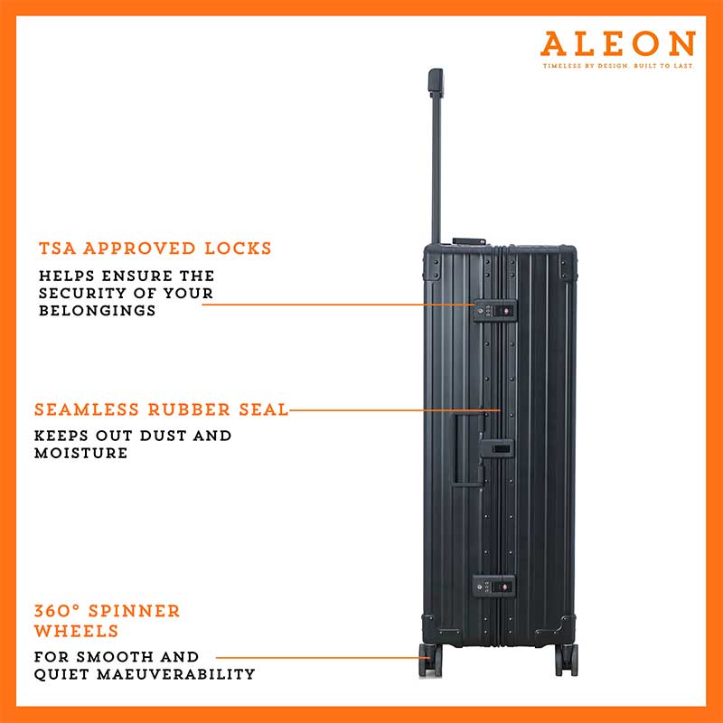 The black ALEON 32″ Macro Plus Traveler, with its brushed aluminum finish, leans against a baggage claim carousel. Its sleek exterior catches ambient lighting, showcasing its premium craftsmanship and refined design built for sophisticated travelers.